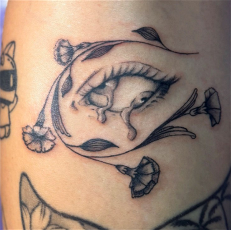 Tatuagem fineline de olho com cravos florais